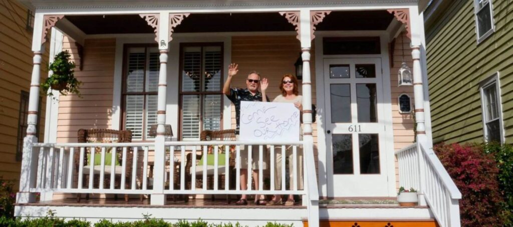 Husband and wife on front porch waving