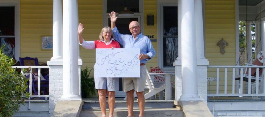 Husband and wife standing on front porch waving