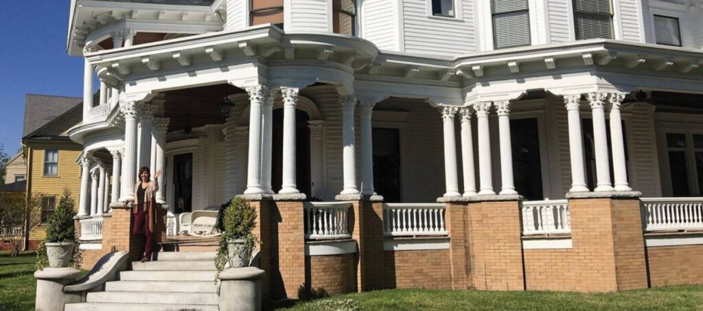 The Blades House with the owner standing on porch waving