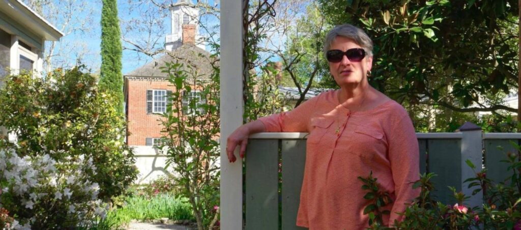 Bethanne Jacobson in her garden leaning an arm on the fence
