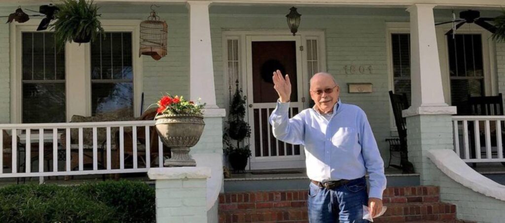 Dana Burham standing in front of him home waving