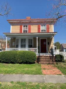 Two story house with wide front porch and red shutters