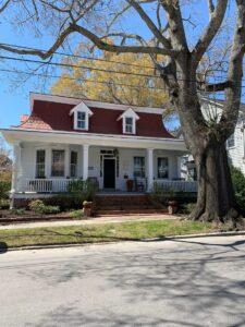Old white house with wide porch and wood roof
