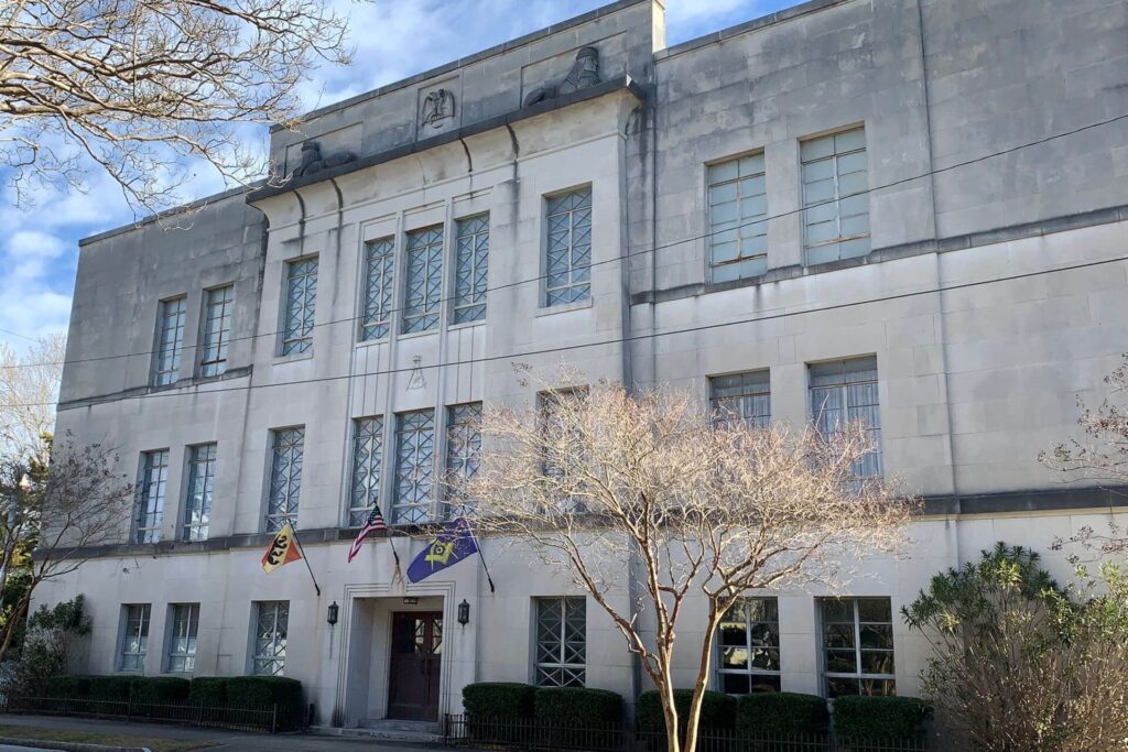Old 3-story stone building with Masonic Lodge plaque and flags