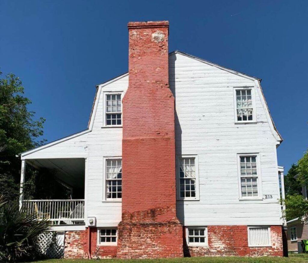 Two story white house, with tall chimney and piazza