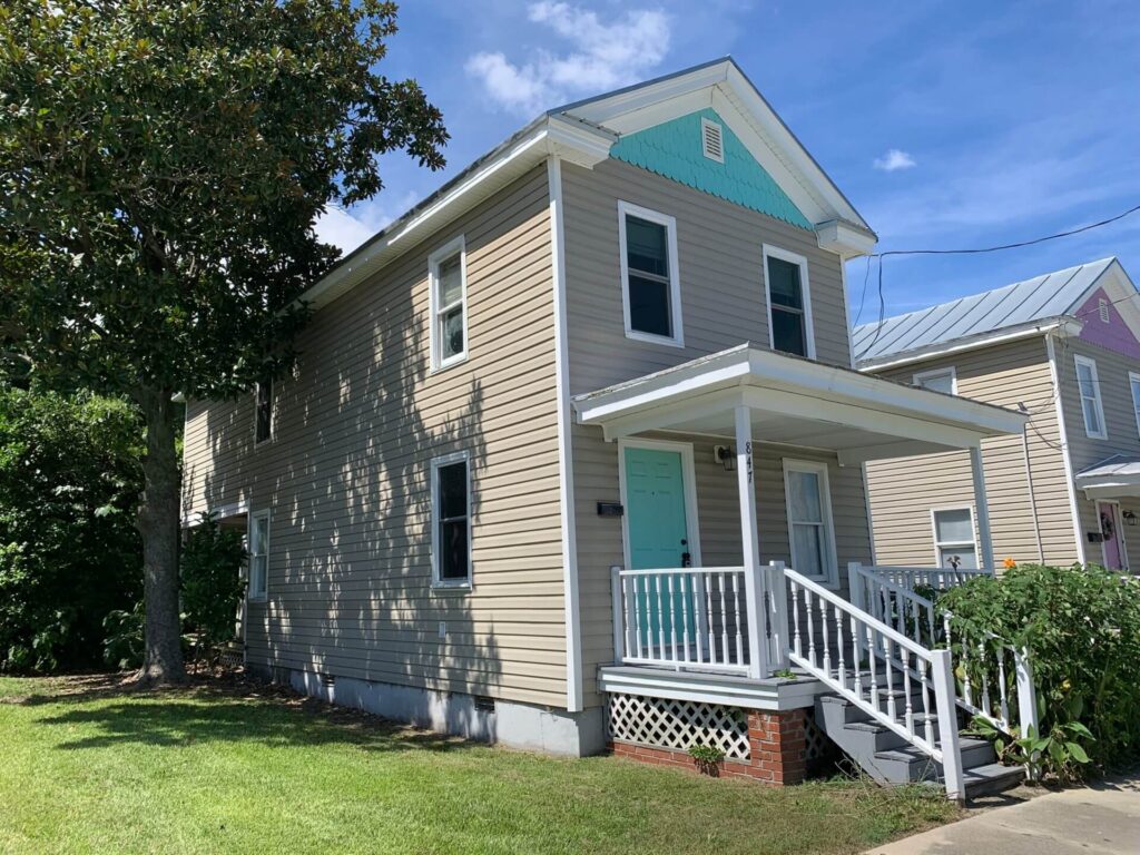Two-story tan house with blue accent paint